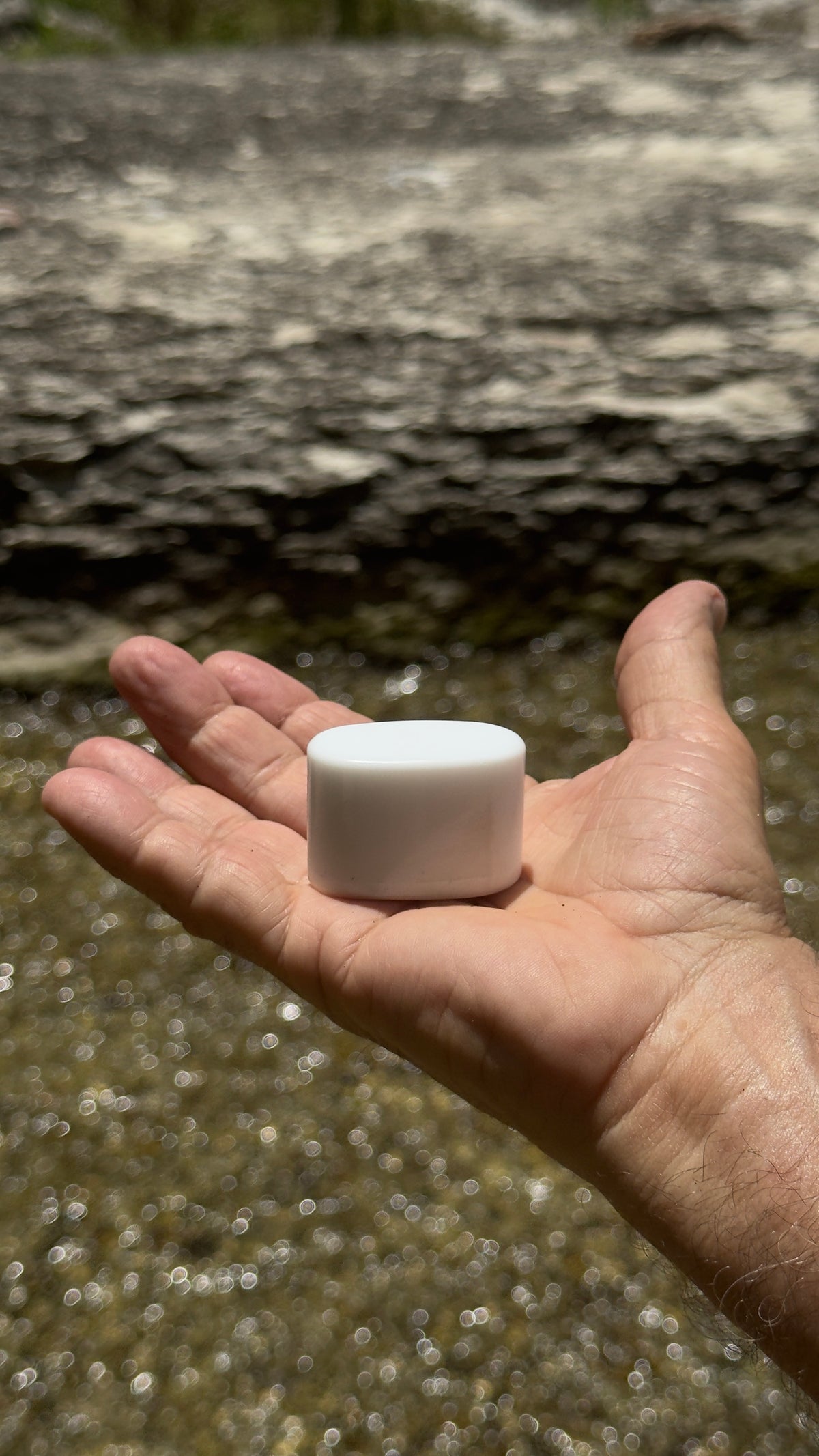 Pocket Mag magnet resting in an open palm beside a creek