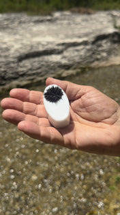 Magic Mag black sand magnet held in hand with magnetite clinging to its face