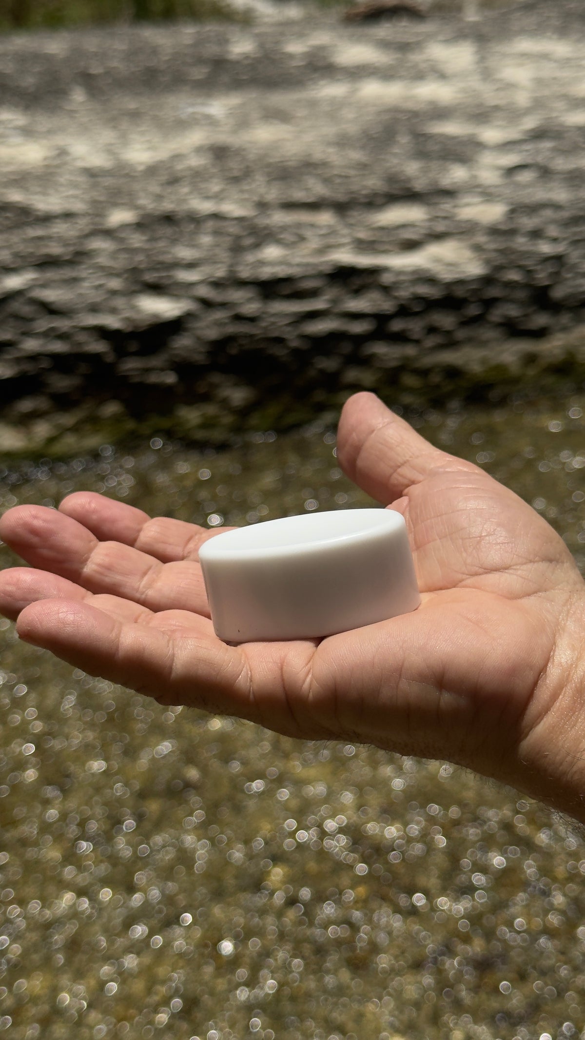 Magic Mag magnet resting in an open palm beside a creek