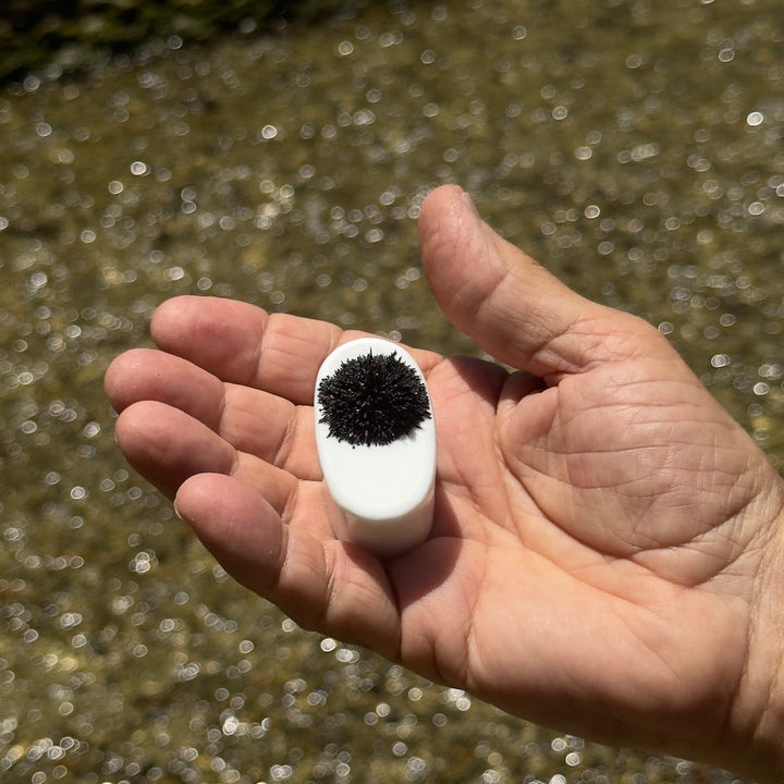 Pocket Mag black sand magnet held in hand with magnetite clinging to its face