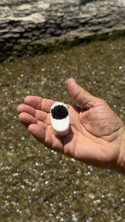 Pocket Mag black sand magnet held in hand with magnetite clinging to its face