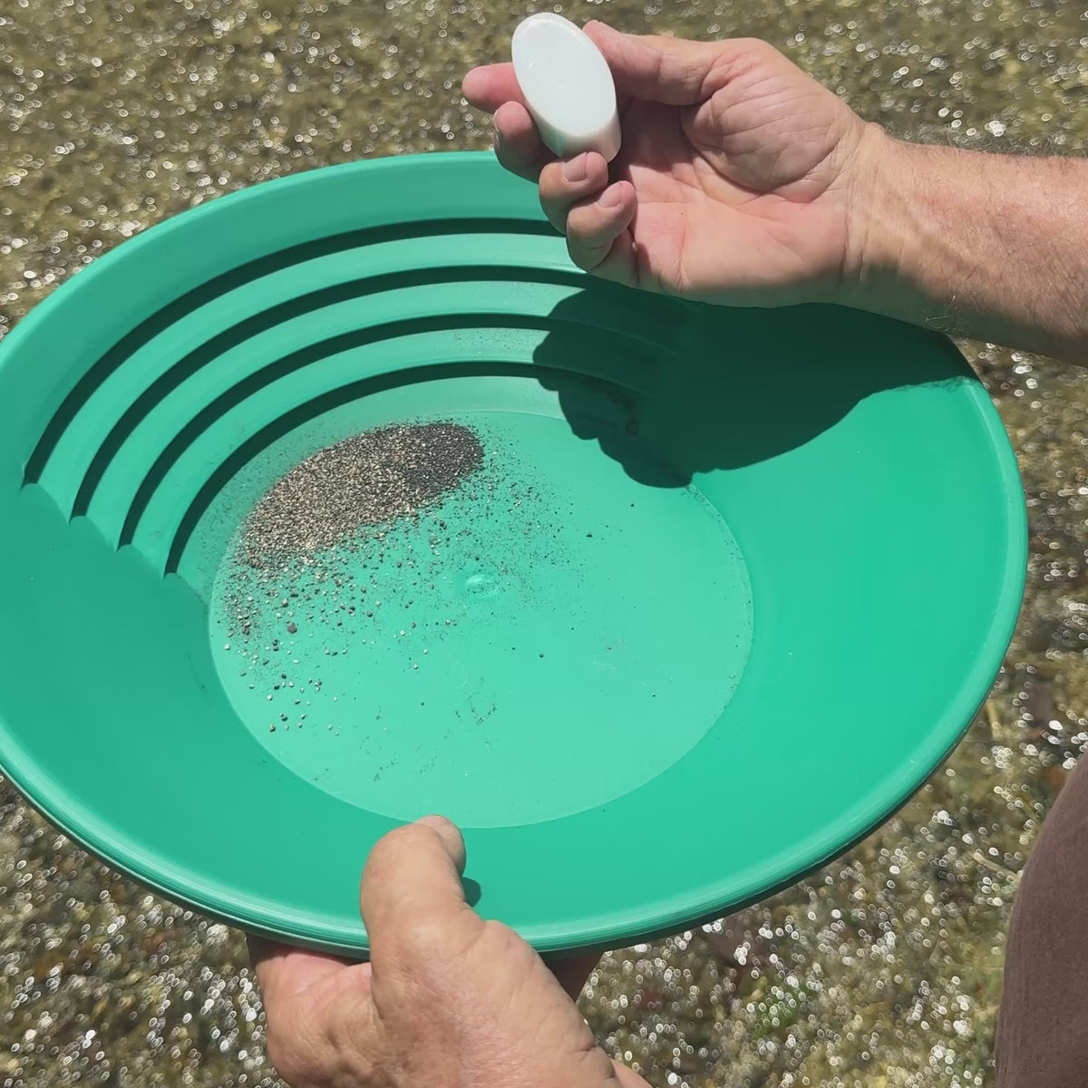 Magic Mag sweeping black sand out of a gold pan